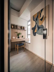 A modern home office with light wood furniture, marble accents, and glass elements.