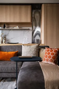 A modern living room with a fabric sofa, marble backsplash, and wooden cabinets.