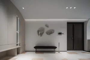 A modern lobby featuring metallic glass panels on the wall and a dark bench.