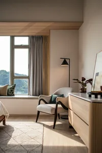 A minimalist bedroom with a wooden armchair, floor lamp, and dresser.