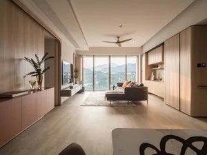 Modern minimalist living room featuring wood-textured walls and furniture, with a view of mountains outside.