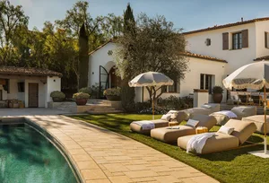 Outdoor lounge area with chaise lounges, umbrellas, and a swimming pool.