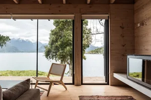 A modern wooden living room with a view of the lake and mountains.