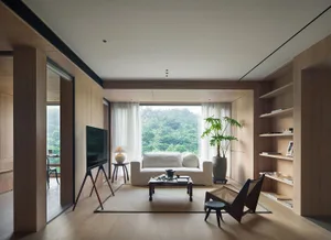Modern minimalist living room featuring white furniture, natural hardwood floors, and large windows with a forest view.
