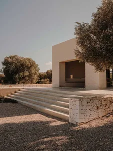 A modern architectural space with a concrete exterior, featuring a central open area surrounded by a stone wall and steps lea