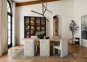 A modern dining room featuring a wooden table, patterned chairs, and a glass-fronted cabinet.