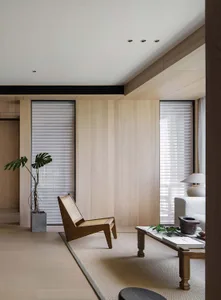 Minimalist living room with wooden furniture, natural light, and plants.