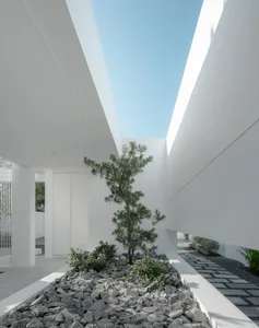 A modern white corridor with glass walls, concrete floors, and steel railings