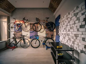 A room with bicycles stored on a metal rack against a wall, featuring a modern interior design with a sports theme.
