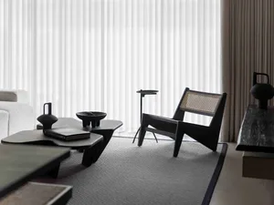 Modern minimalist living room with black furniture, white curtains, and a textured rug.