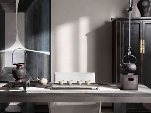 A minimalist tea room featuring ceramic teapot, metal kettle, and wooden table.
