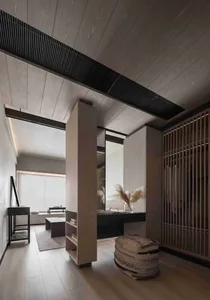 Modern minimalist bedroom with walnut wooden furniture and plush rug, featuring a sleek, low-profile bed and a cozy lounge ar