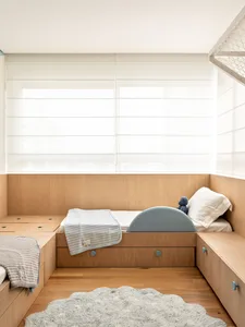 A minimalist bedroom featuring wooden beds with built-in storage and soft textiles.