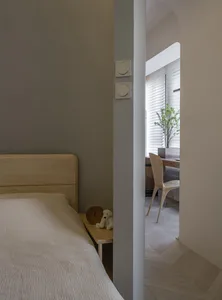 A minimalist bedroom featuring a wooden nightstand with a clock and a stuffed animal.