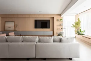 A modern minimalist living room featuring wooden furniture and a large window with plants.