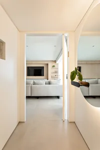 Modern minimalist living room with white furniture and concrete flooring.