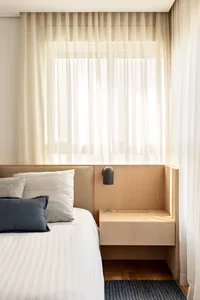 A modern bedroom featuring wooden furniture and neutral-colored bedding.
