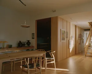 A modern dining room with wooden furniture and flooring.