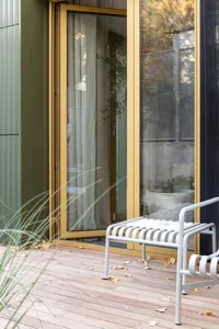 Modern residential entrance featuring wood flooring, metal bench, and potted plants