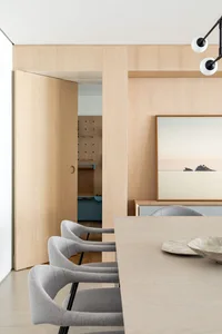 A modern interior design featuring a wooden table and chairs, with a minimalistic art piece on the wall.