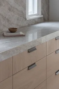 A modern kitchen with minimalist design featuring a marble countertop and cabinets.