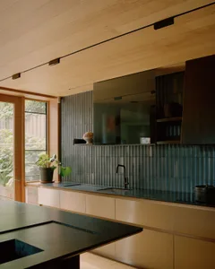 A modern kitchen featuring metallic tiles backsplash and wood cabinets.