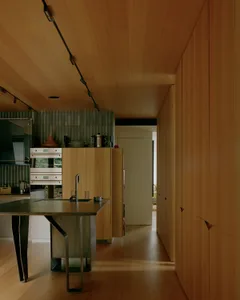 A modern kitchen featuring wooden cabinets and a stainless steel island with a sink and faucet.