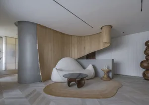 Modern living room with a wooden spiral staircase, a white sofa with a unique design, and a glass coffee table on a textured 