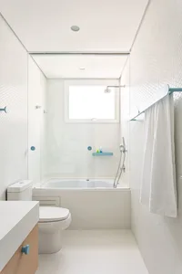 A modern minimalist bathroom featuring white tiles and glass elements.