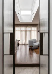 A modern minimalist living room featuring soft furnishings and wooden flooring.