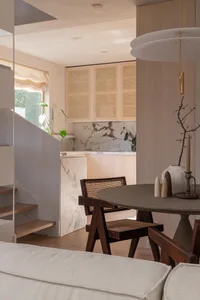 A modern residential interior featuring marble countertops and a concrete dining table.