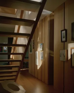 A modern staircase with wooden beams and framed artworks on the walls.