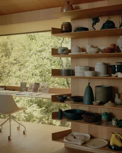 A well-organized craft shop displaying various ceramic pottery and sculptures on wooden shelves.