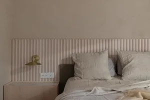 Modern minimalist bedroom featuring wooden headboard paneling and neutral bedding.