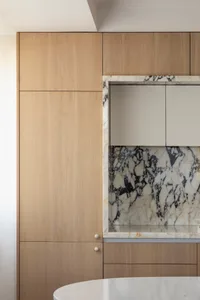 A minimalist kitchen with wooden cabinets and a marble backsplash.