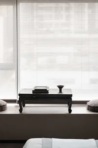 A minimalist residential interior features light wood, fabric, and glass materials.