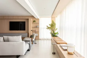 Modern living room with minimalist design, white sofas, wooden accents, and large windows.