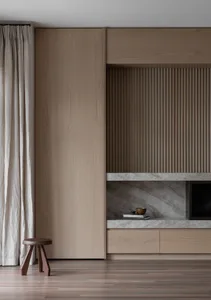 A minimalist living room featuring a modern wood cabinet and a window with curtains.