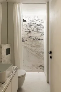 Modern minimalist bathroom with white marble walls and floor.