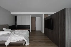 A modern minimalist bedroom with dark wood paneling and a white bedspread.