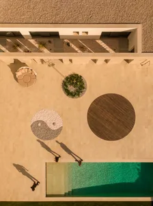 Minimalist design featuring a concrete patio with a yin-yang symbol, a wooden deck, and a swimming pool.