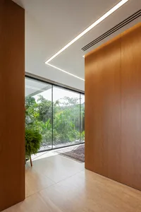 A modern minimalist residential lobby with wooden walls and large windows overlooking greenery.