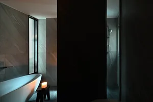 A modern bathroom with minimalist design, featuring a freestanding bathtub and a shower area with concrete tiles and a window