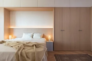 Modern bedroom featuring a bed with wood headboard and concrete floor, illuminated by soft ambient lighting.