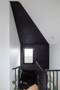 A modern black staircase interior with wooden paneling and a window.