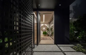 Modern entrance with glass and metal gate, concrete paving and potted plants
