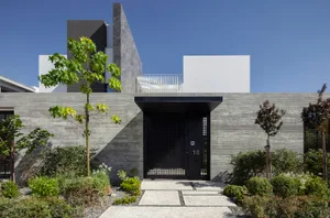 A modern exterior house with concrete walls and a black entrance gate.