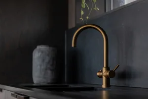 A close-up of a modern kitchen with a metallic brass faucet and a black countertop.