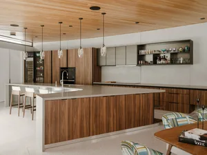 A modern residential kitchen featuring wooden cabinets, stone countertops, and metallic accents.