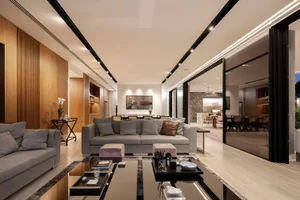 Modern living room interior with hardwood floors, large glass panels, and fabric seating.